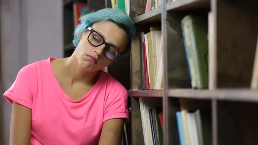 女大学生沮丧地靠在图书馆书架视频