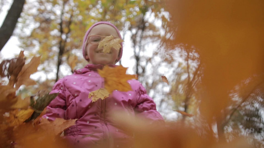 女孩在秋天的公园里扔着枫叶视频