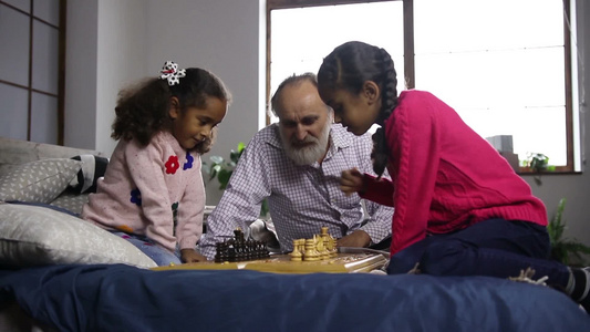 可爱的小妹妹在英俊的祖父的帮助下下棋视频