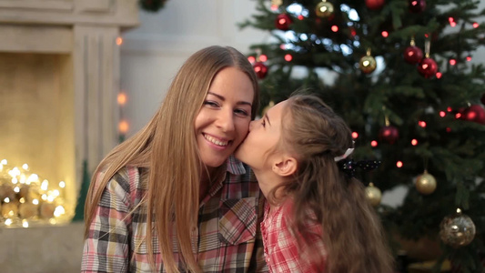 可爱的小女孩在圣诞节亲吻她美丽的母亲视频