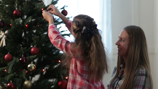 小女儿和母亲在圣诞树上挂装饰品视频