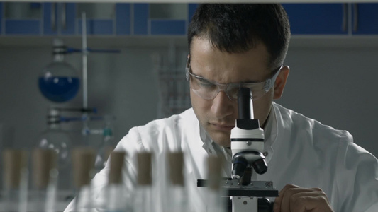 英俊的男性科学家在实验室中进行显微镜分析视频