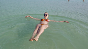 年轻的孕妇在死海的盐水里游泳5秒视频