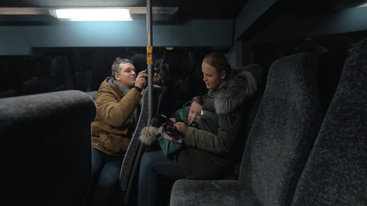 男人在车上拍摄女人和儿子一起玩智能手机视频