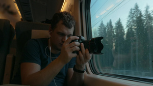 男士靠在火车窗上用相机拍摄窗外29秒视频