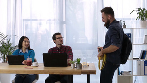 快乐的时髦企业家拿着网球拍当吉他手在创意办公室里14秒视频