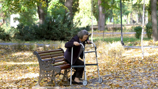 年长的女人从长凳上站起来在秋天的公园里户外散步视频