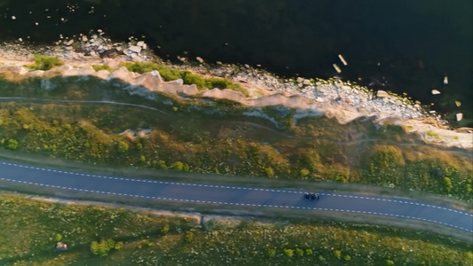 空中拍摄黑色汽车行驶在海边悬崖附近的道路上视频