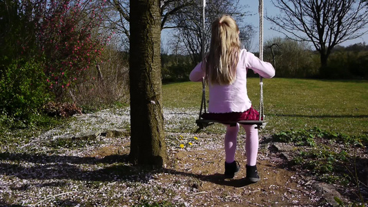 一个小女孩坐在树林里荡秋千视频