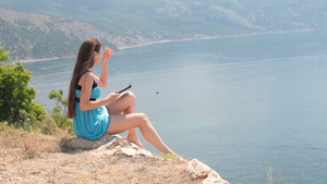 年轻女孩坐在悬崖上阅读电子书22秒视频