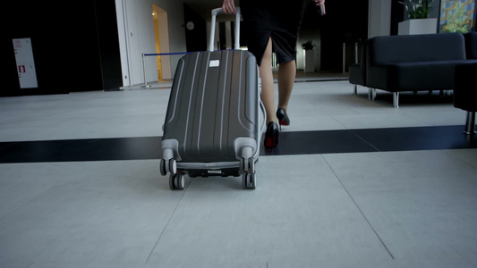 商务妇女穿着正式的衣服带着一个带轮子的袋子在机场楼视频