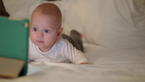 一个可爱的女婴躺在大床上看着她前面的平板电脑12秒视频
