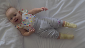 女婴穿着圆点衬衫躺在白色的床单上10秒视频