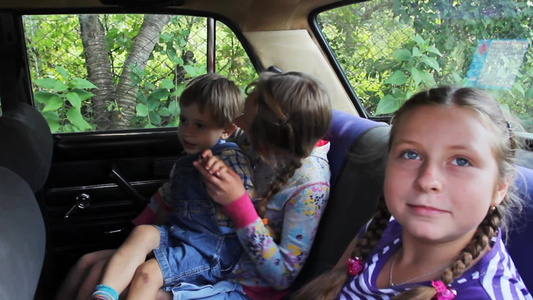 两个姐妹很高兴坐在车里的后座和弟弟一起玩视频