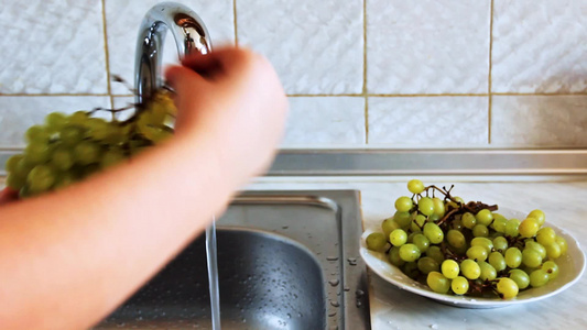 少女的手打开水龙头清洗绿色葡萄视频