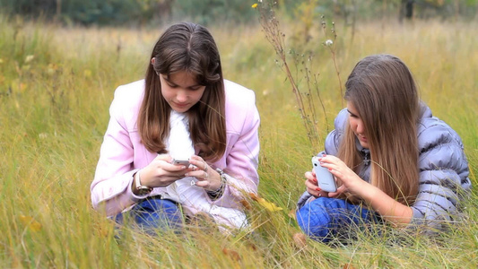 公园玩手机的两个女孩[品牌手机]视频