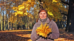 美丽的秋天城市公园里漂亮的女人手里拿着一束黄叶做成地花朵7秒视频
