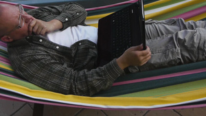 躺在吊床上看笔记本电脑的男人6秒视频