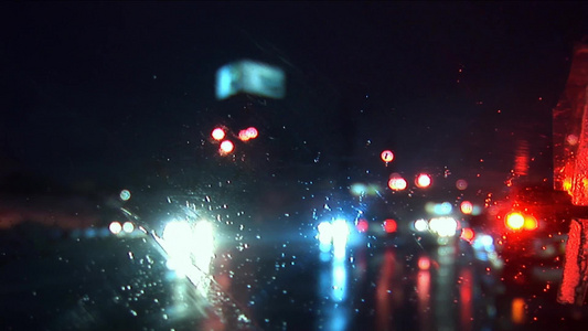 下雨的夜晚坐在行驶的汽车内通过车窗玻璃向外拍摄的道路夜景[窗棱]视频