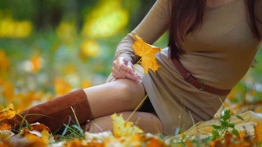 坐在公园草地上感受秋季的年轻女人视频