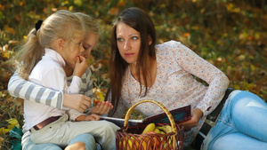 年轻的母亲和两个女儿在秋天的公园野餐15秒视频