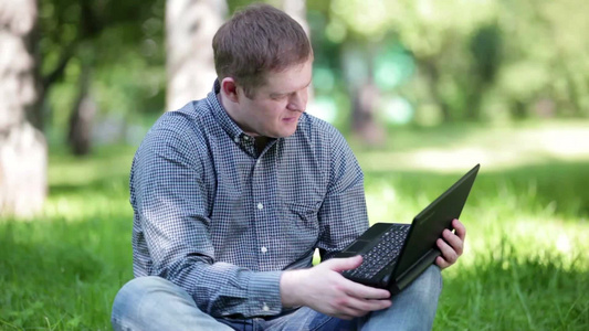 年轻的男人在公园里用笔记本工作视频