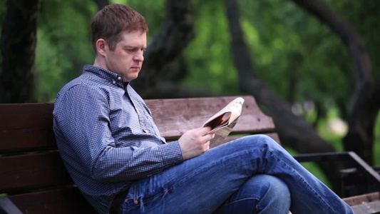 男人在公园的长凳上看报纸[条凳]视频