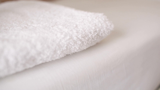 女人把一条白色毛巾放在床上抚平视频