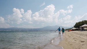 一对年轻的夫妇在冲浪的边缘手拉手地沿着海滩跑步12秒视频