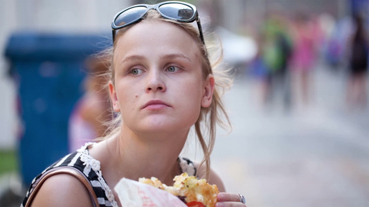 年轻的女人头上戴着太阳镜在街上吃快餐视频