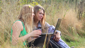 两个女性朋友坐在草地上用笔记本电脑在线交谈14秒视频