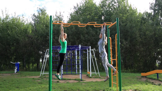 两个女孩在公园里使用健身器材[单双杠]视频