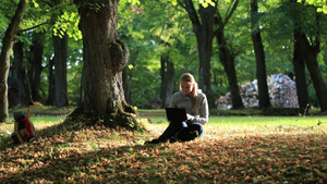 年轻的女人坐在公园的草坪上用笔记本电脑聊天25秒视频