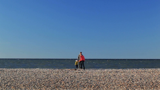 母亲父亲和儿子走在鹅卵石的海滩上[河卵石]视频