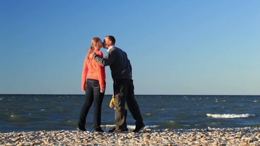 一家三口站在鹅卵石海滩男人亲吻他的妻子和孩子[湿吻]视频