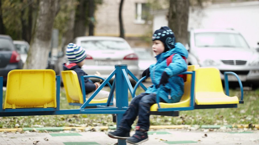冬日里两个孩子坐在户外的旋转木马上[冬意]视频