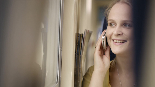 年轻的女人在火车上打电话看着窗外视频