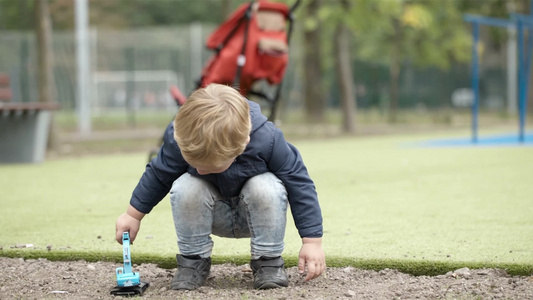 小男孩在户外玩玩具挖掘机视频