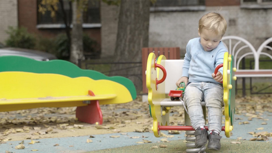 小男孩带着他的玩具拖拉机在秋千上摇摆[小四轮]视频