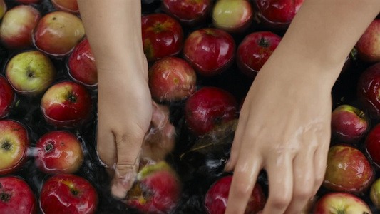 女人清洗漂浮在水里的新鲜苹果视频