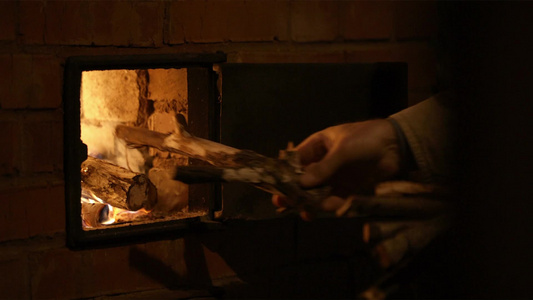 男人的手打开炉门把木柴放在火里视频
