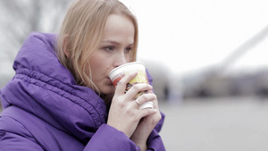 年轻女人在寒冷的天气里吃快餐喝热茶21秒视频