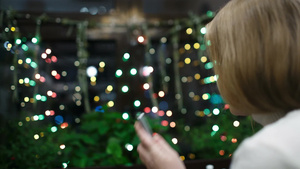 闪烁的圣诞花环旁的女子在接电话18秒视频