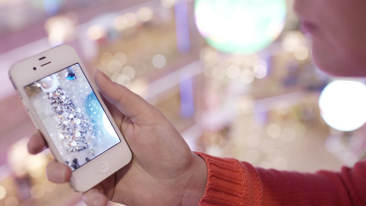 女人在智能手机里看圣诞树的照片视频