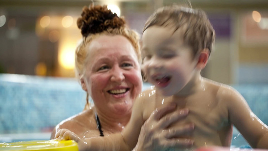 奶奶帮孙子跳在游泳池里男孩拿着漂浮装置视频