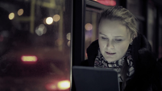 年轻的女人在晚上乘坐公共汽车时用ipad看视频视频