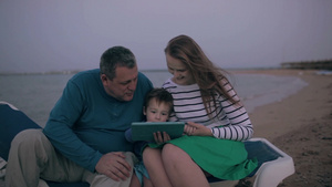 一家三口坐在海边玩平板电脑15秒视频