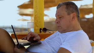 度假期间男人在海滩上用笔记本电脑办公23秒视频