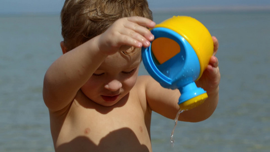 小男孩在海滩上玩水壶视频