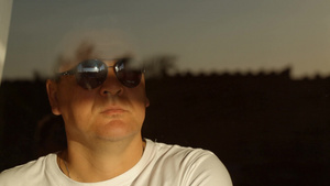 男子戴着太阳镜打开白色窗帘看着窗外17秒视频